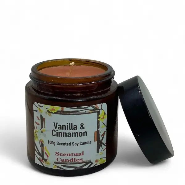 Vanilla & Cinnamon scented candle in an amber jar with a black lid on a white background