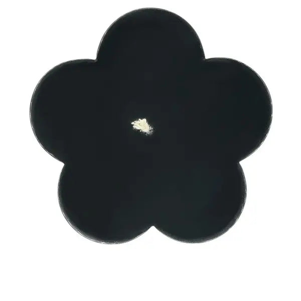 Black flower-shaped candle viewed from above on a white background