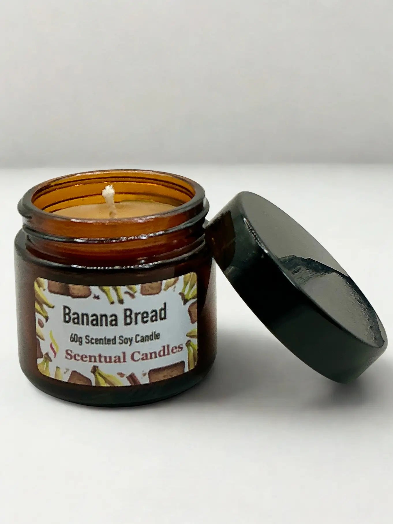 Banana Bread scented candle in an amber jar with a black lid on a white background