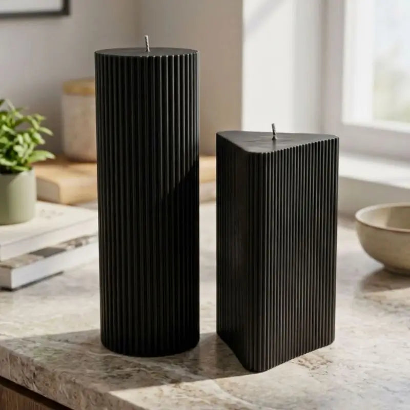 Geometric Pillar Candle set featuring ribbed triangle and tall column in black on a countertop.