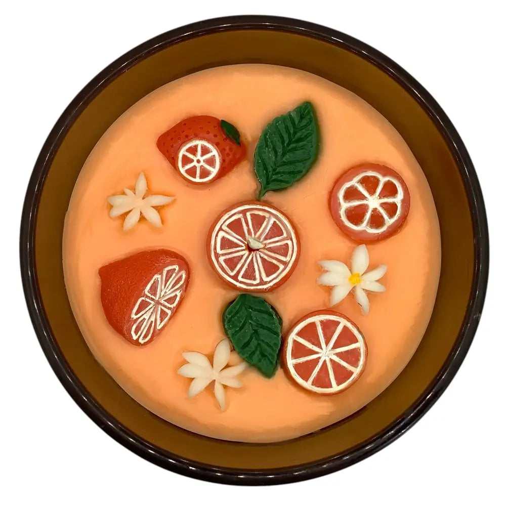 Decorative candle top with fruit and flower designs on a white background
