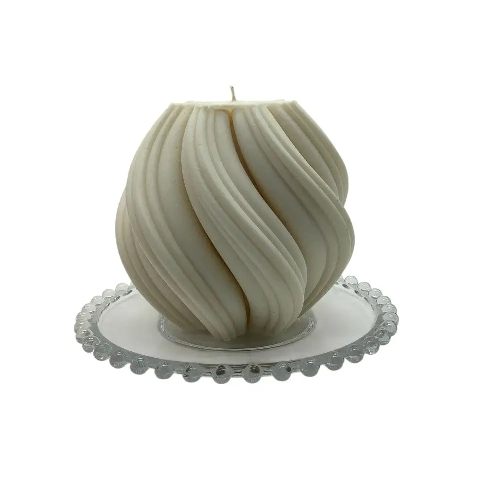 White sculptural candle on a decorative glass candle plate with white background
