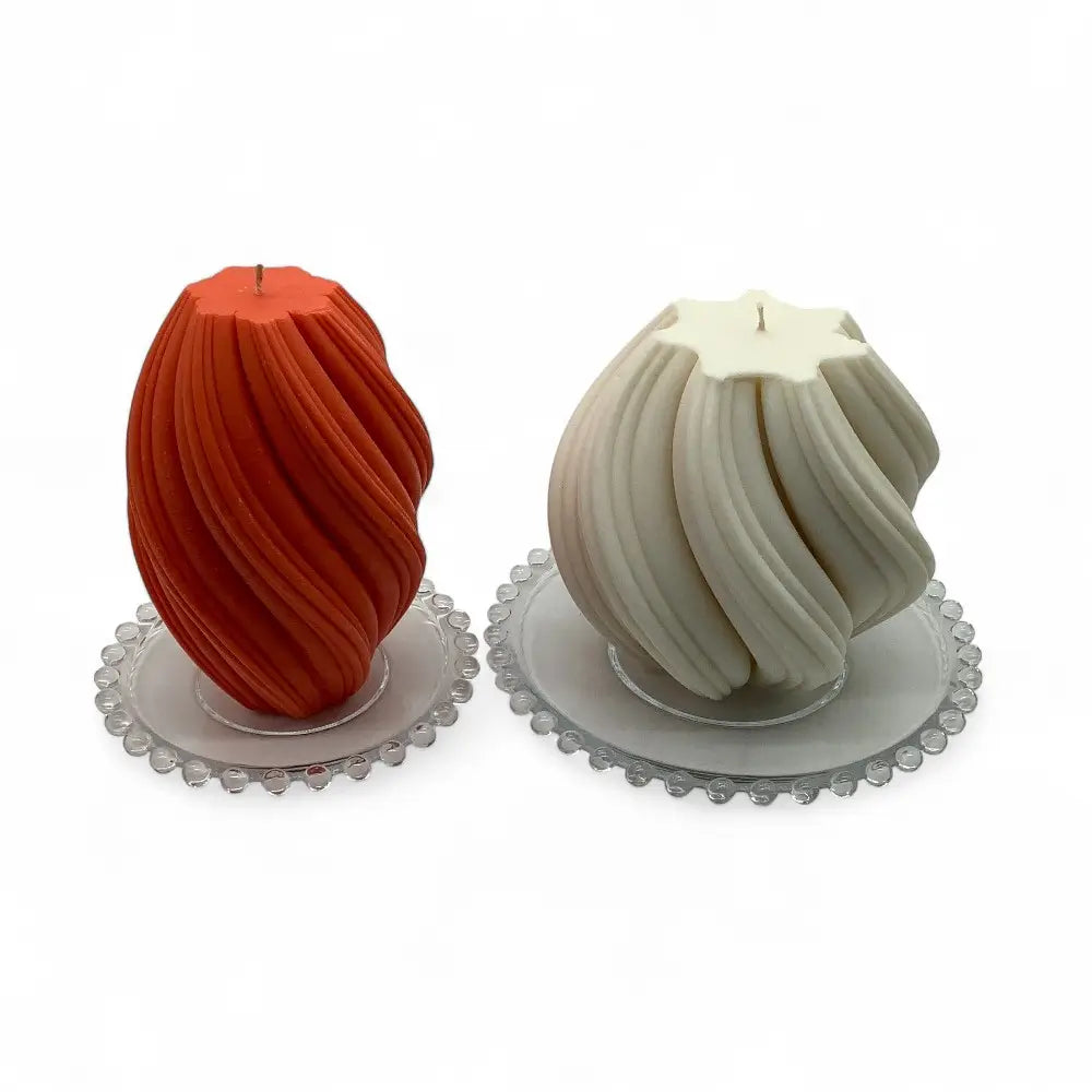 Two large candles on decorative glass candle plates with a white background