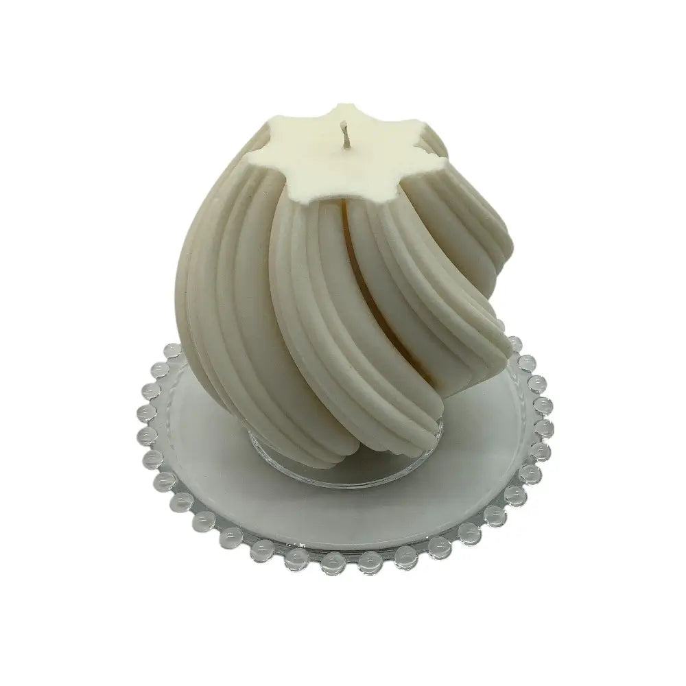 White sculptural candle on a decorative glass candle plate with white background