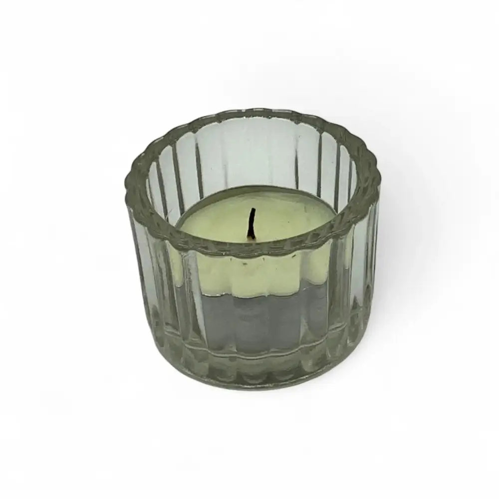 Green candle in a textured glass candle holder on a white background