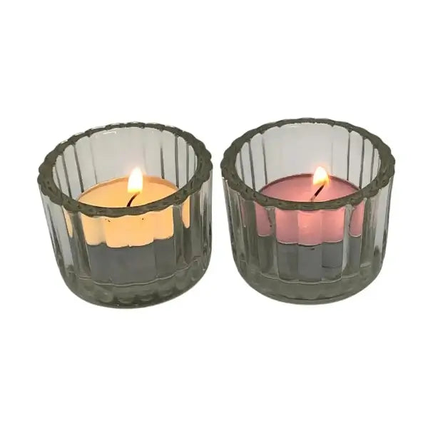 Two lit candles in clear glass candle holders on a white background