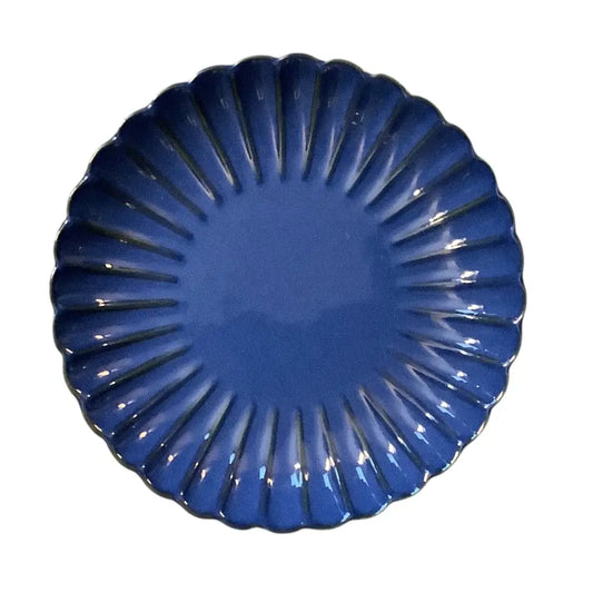 Blue decorative ceramic candle holder plate with a fan-like design on a white background