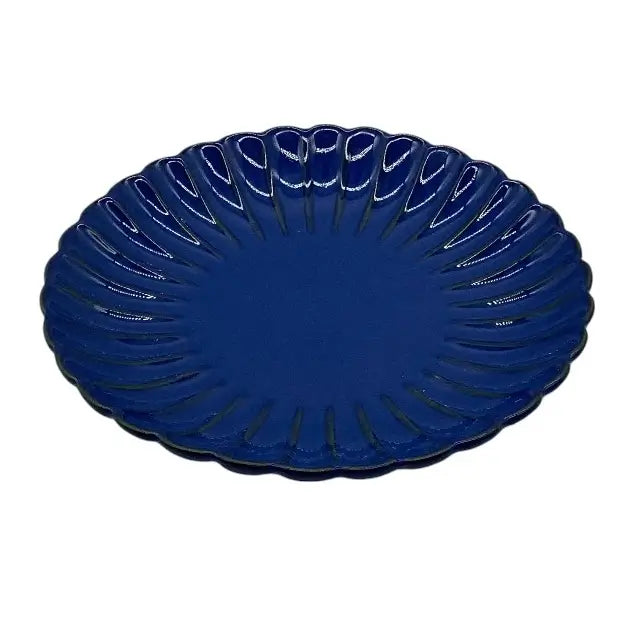 Blue ceramic candle holder plate with decorative edge on a white background