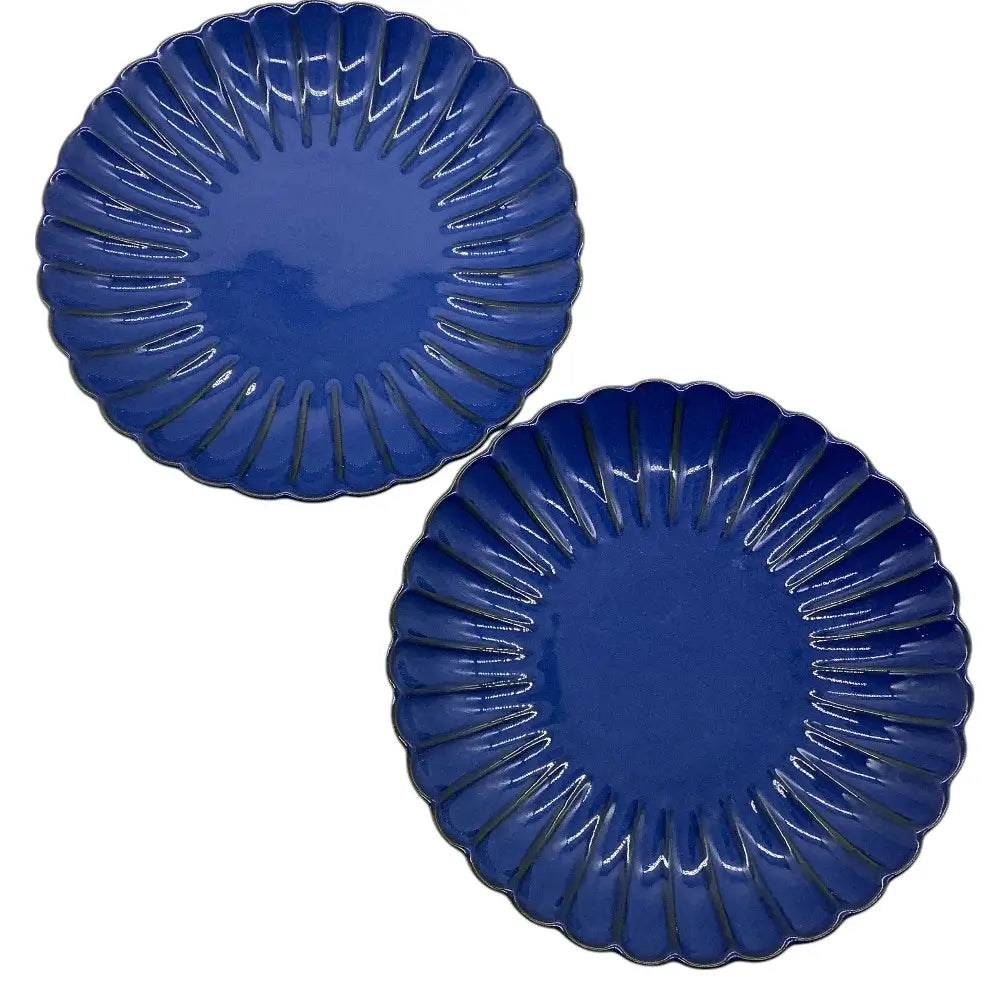 Two blue ceramic candle holder plates with decorative edges on a white background