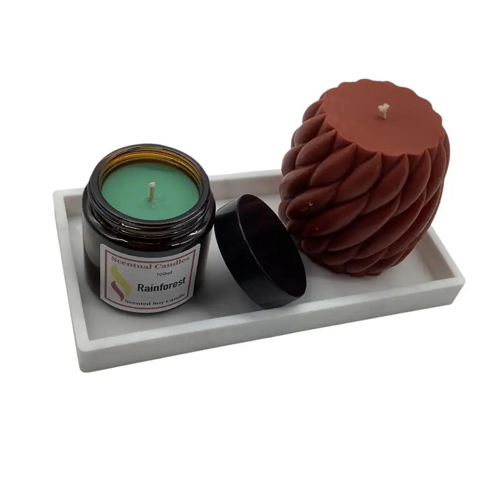 Two candles, one in a jar and one spiral-shaped, on a white tray with a white background.
