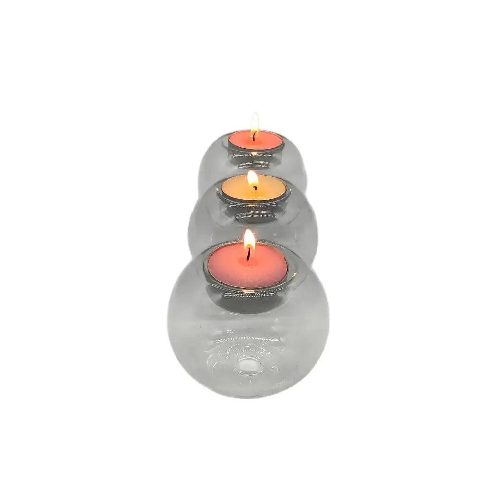 Three clear glass candle holders with lit candles on a white background