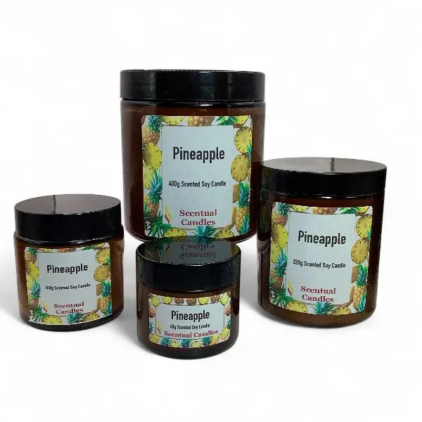 Four scented candles with pineapple-themed labels on a white background