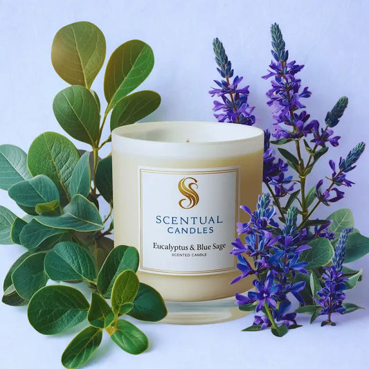 Blue Sage & Eucalyptus candle with green leaves and purple flowers on a light blue background