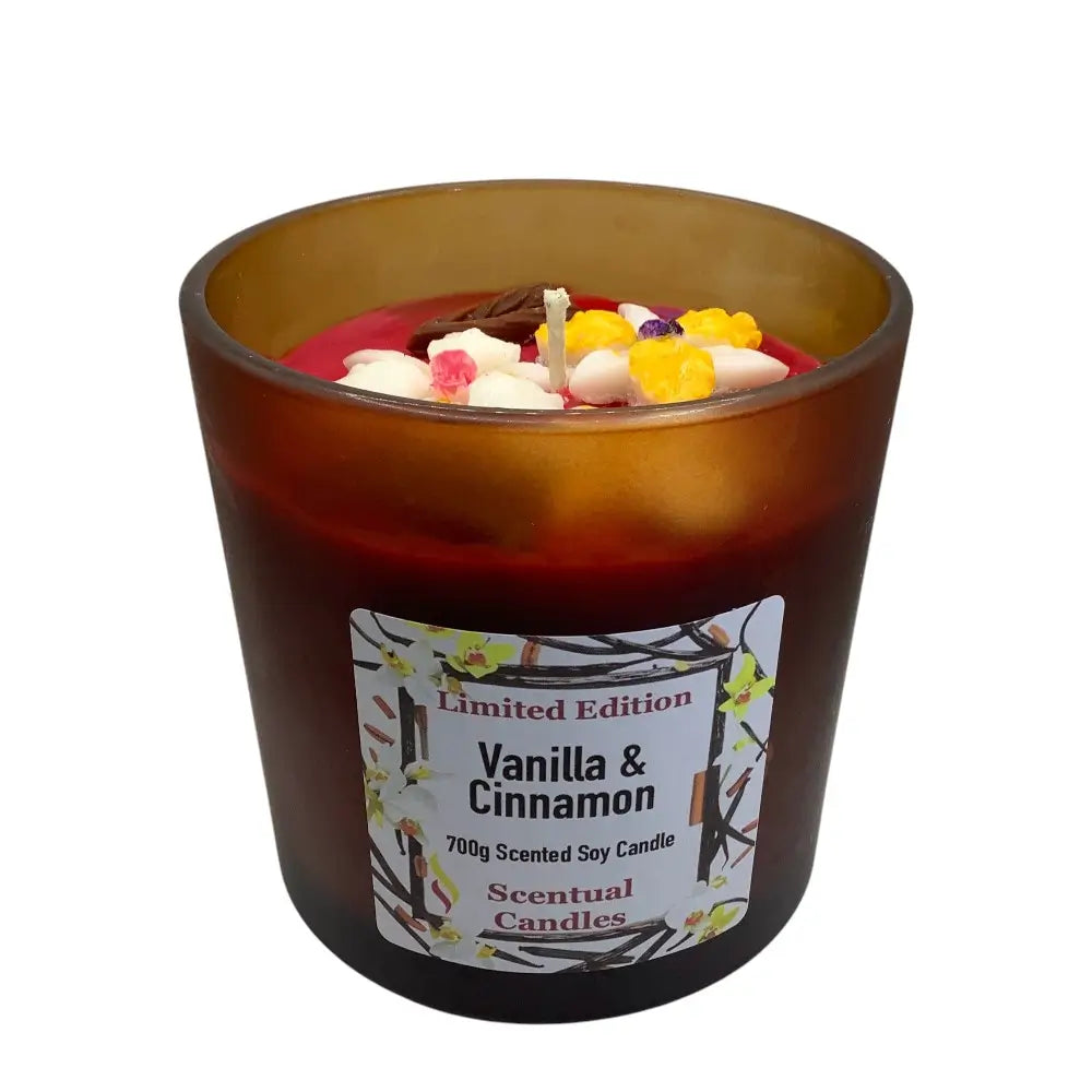 Vanilla & Cinnamon scented candle with decorative elements in a brown glass container on a white background.