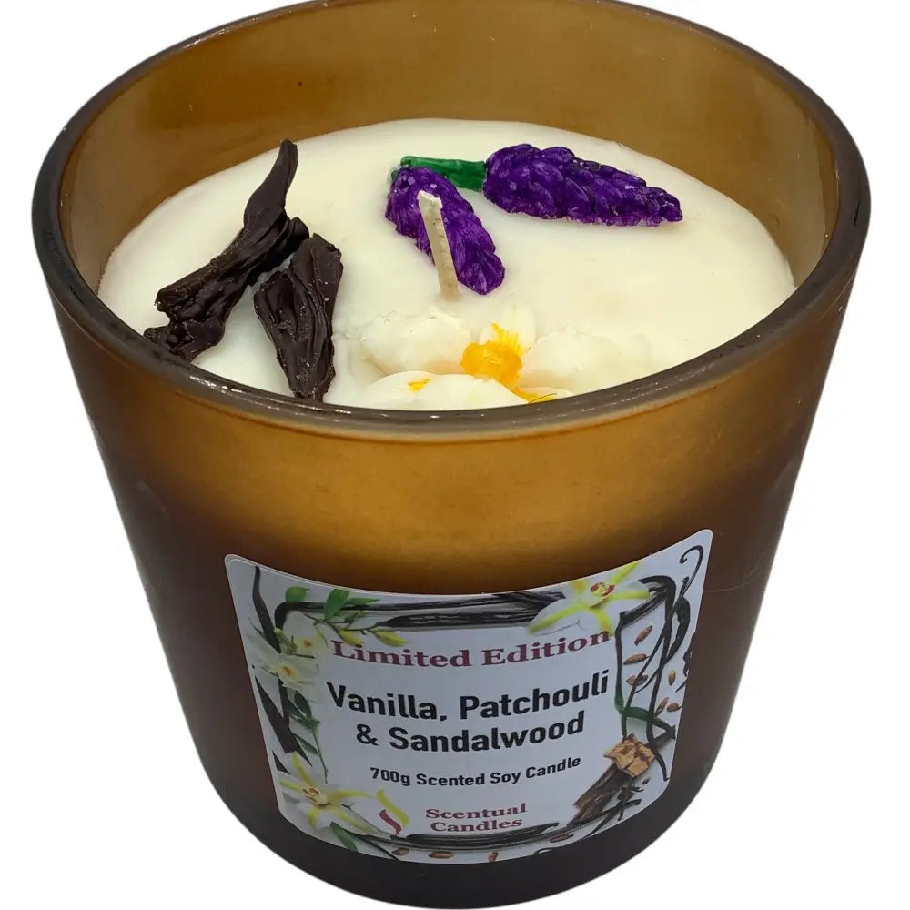 Scented candle with vanilla, patchouli, and sandalwood fragrance in a brown glass container.