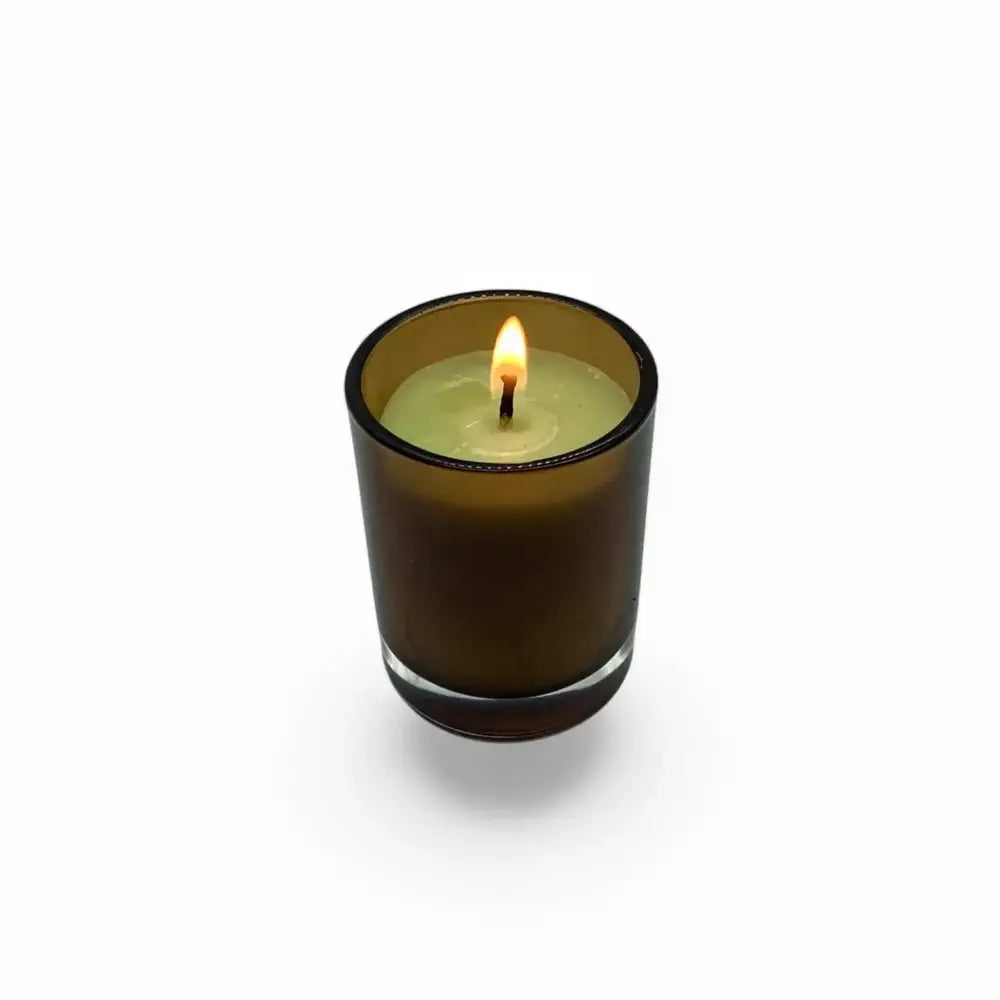 Amber glass votive candle holder with lit candle inside, 7cm height, 5cm diameter, warm cozy ambiance.