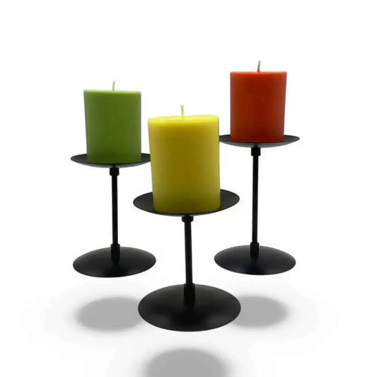 Three piece wrought iron candle stands with matte black finish and colored candles displaying elegant trio design.