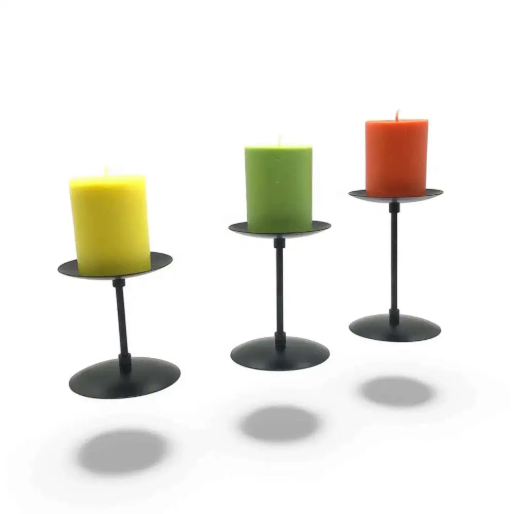 Three-piece matte black wrought iron candle stands with varying heights and pillar candles.