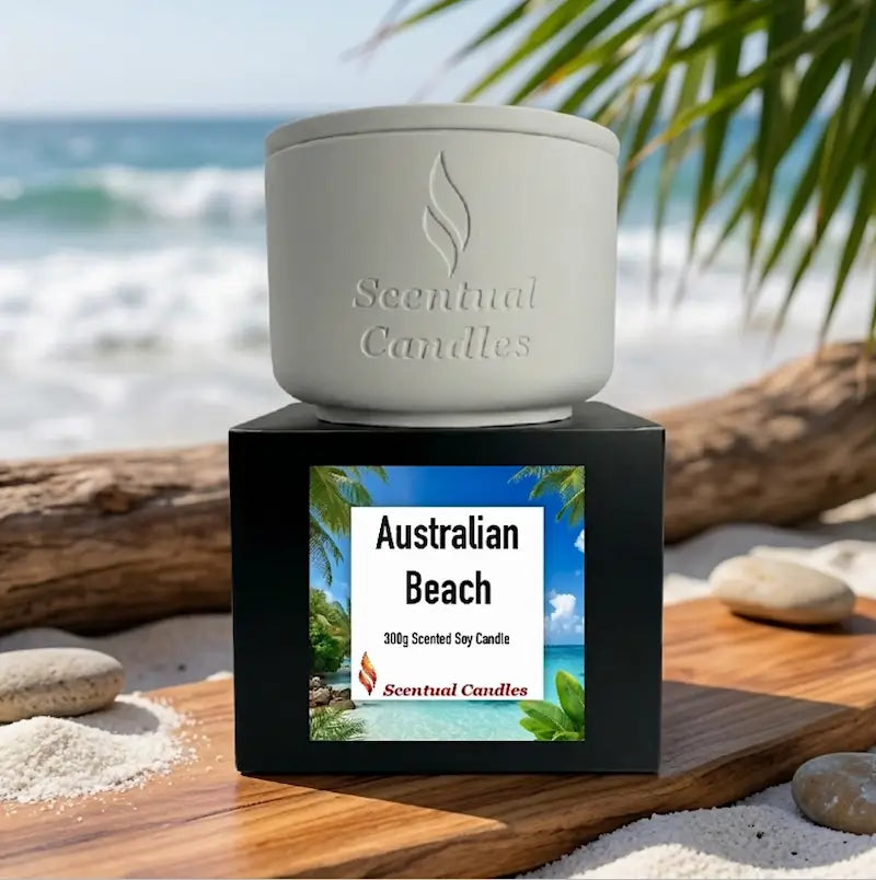 Beach Candle sits on a wooden surface by the ocean, featuring Australian Beach scent with palm leaves in the background.