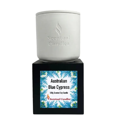 Australian Blue Cypress Candle displayed in a white container on a black base with vibrant packaging.