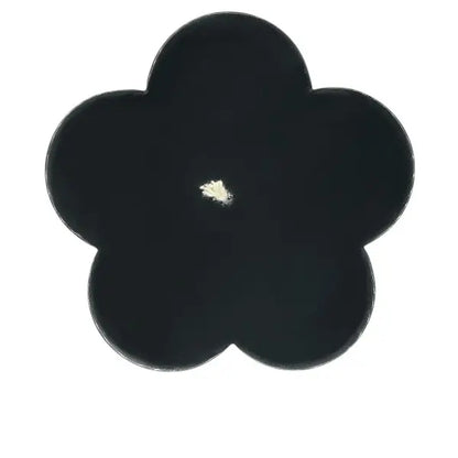 Black vanilla flower-shaped candle viewed from above on a white background