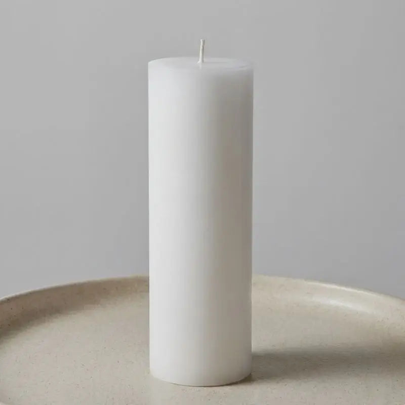 White Pillar Candles on a neutral plate, showcasing the elegant and minimalist design.