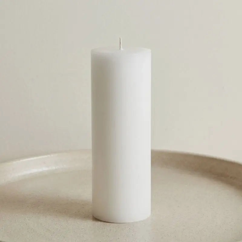 Vanilla Patchouli and Sandalwood white pillar candle on a minimalist ceramic plate.