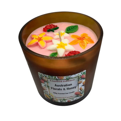 Scented candles with floral decorations in a brown glass jar on a white background