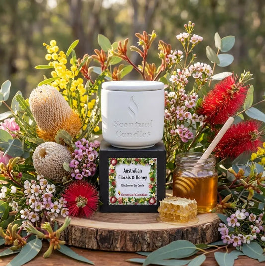 Aromatherapy candle with Australian Florals and Honey theme surrounded by flowers and honey on a wooden stand.
