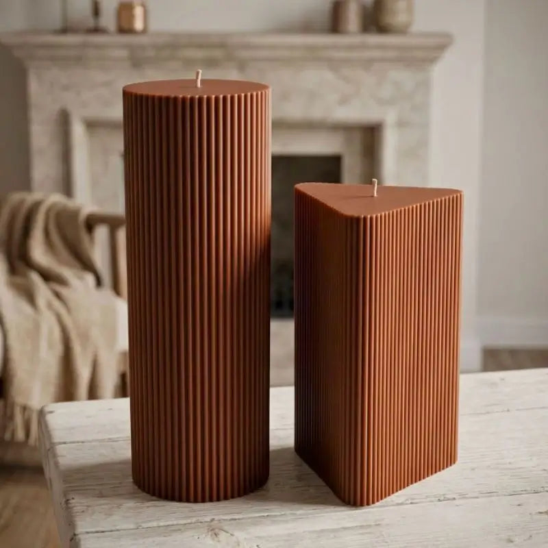 Geometric Pillar Candle set featuring a tall ribbed column and a shorter ribbed triangle on a wooden table.