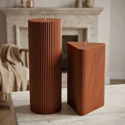 Geometric Pillar Candle set featuring a tall ribbed column and a shorter ribbed triangle on a wooden table.