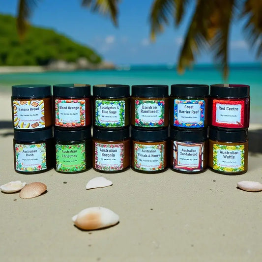 Candle Gift Set - 12 Australian Scents displayed on beach with tropical background. Experience distinctive fragrances from Australia's diverse regions.