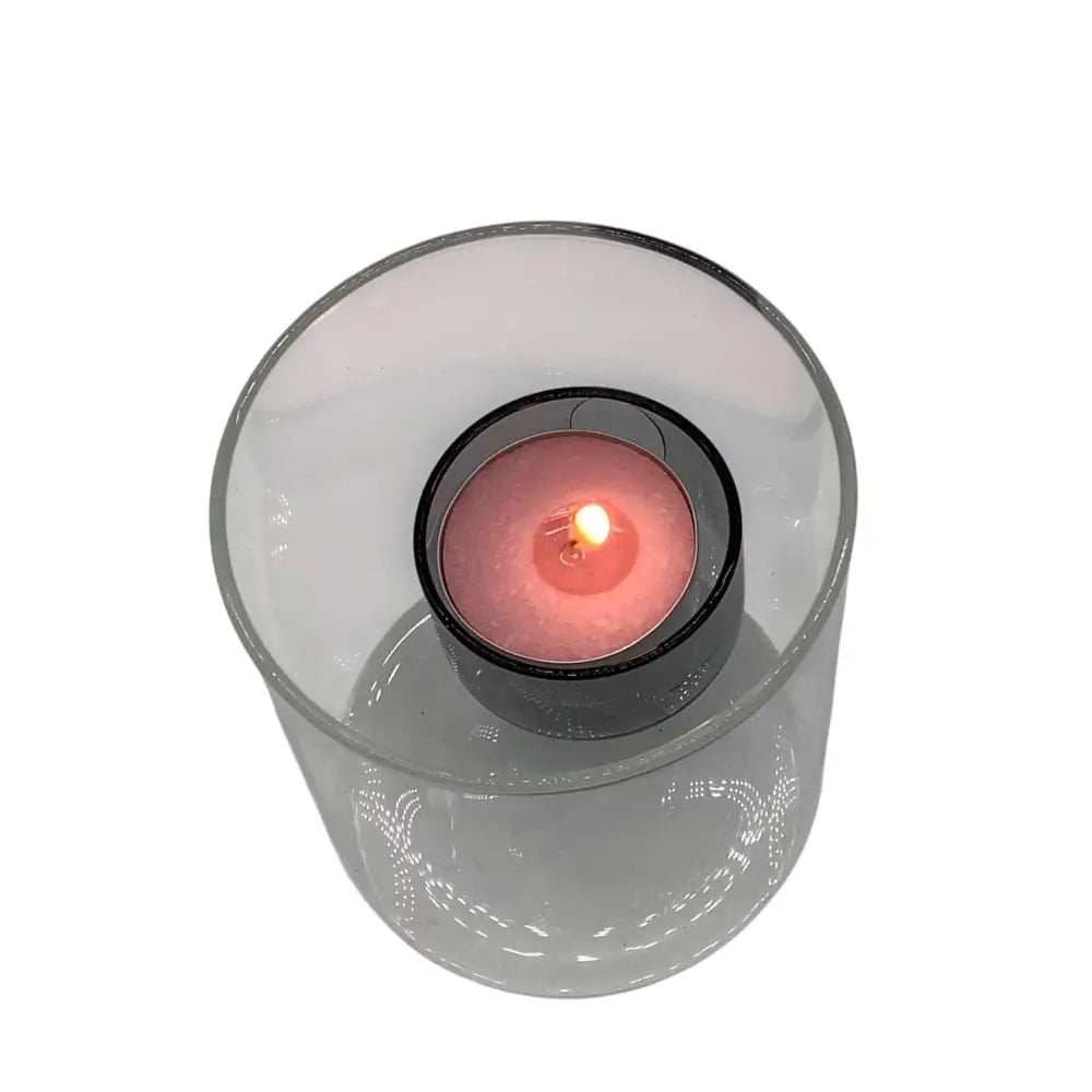 Clear glass candle holder with a red candle inside on a white background