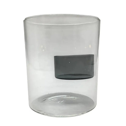 Clear glass candle holder with a black candle inside on a white background