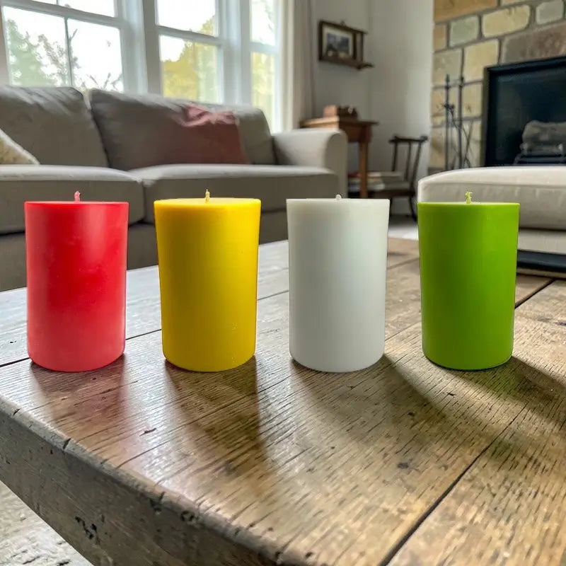 Four Extra Large Pillar Candles in different colors on a wooden table, perfect for home decor and fragrance.