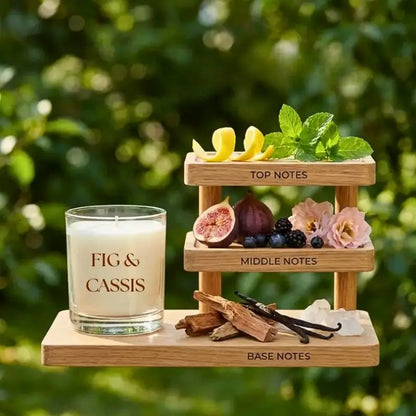 Fig and Cassis scented soy candle displayed with fruit and botanical notes on a wooden shelf.