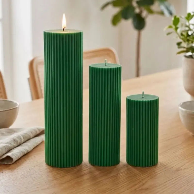 Ribbed Candles - Set of 3 Pillars in green on a wooden table, featuring various heights and vertical ribbing.