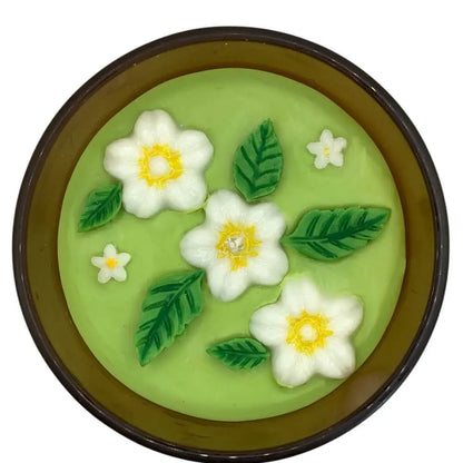 Decorative scented candles top with floral designs on a green background