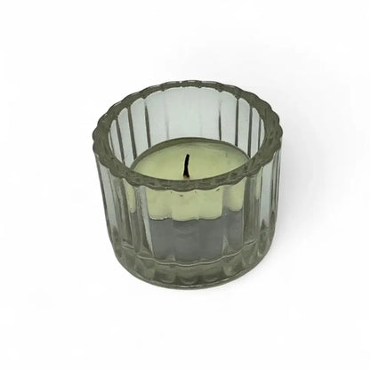 Green candle in a textured glass candle holder on a white background