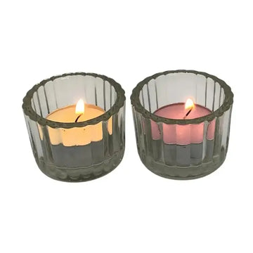 Two lit candles in clear glass candle holders on a white background