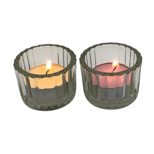 Two lit candles in clear glass holders on a white background