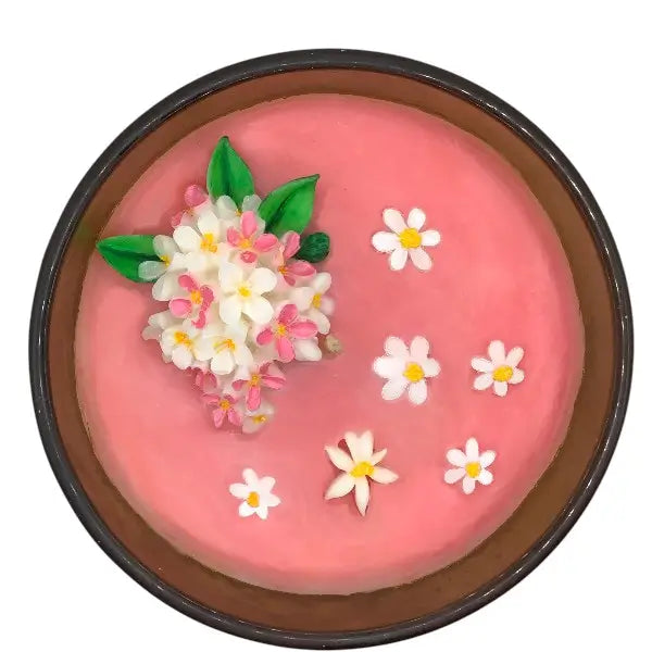 Pink scented candles top with floral decorations in a brown jar