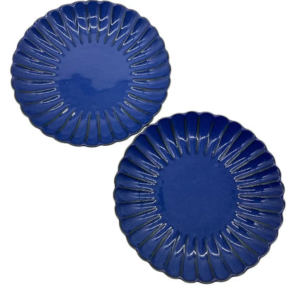 Two blue ceramic candle holder plates with decorative edges on a white background