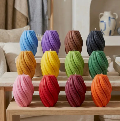 Collection of Large Pillar Candles in swirly shapes with various colors arranged on a wooden table.