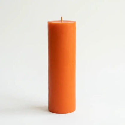Big Candle in vibrant orange color standing tall on a simple background, perfect for adding bold décor.