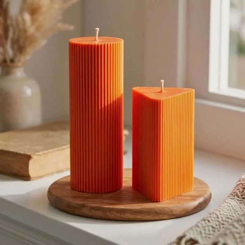 Geometric Pillar Candle set featuring ribbed orange candles in a sculptural display on a wooden tray.