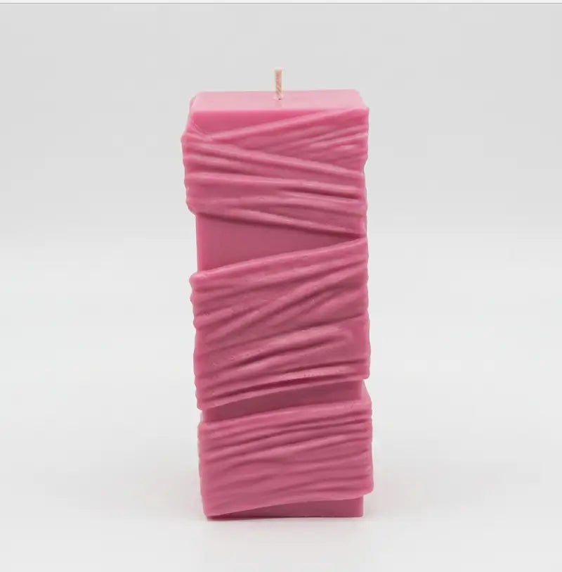 Custom Candle - Large Sculptural Design in pink with textured details and a wick on top.