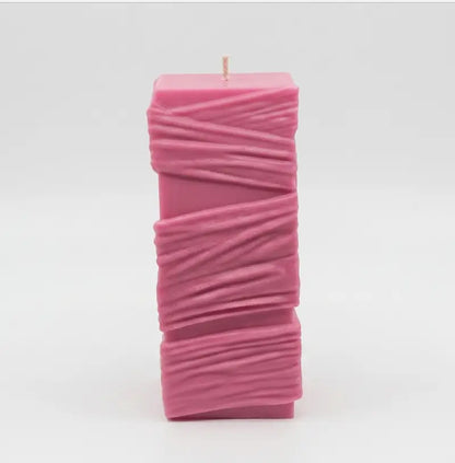 Custom Candle - Large Sculptural Design in pink with textured details and a wick on top.