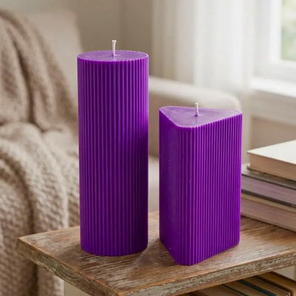 Geometric Pillar Candle set featuring a tall ribbed column and a triangle candle in purple on a wooden table.