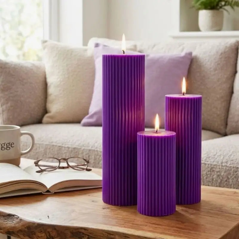 Ribbed Candles in purple displayed on a coffee table, featuring three pillar candles of varying heights.